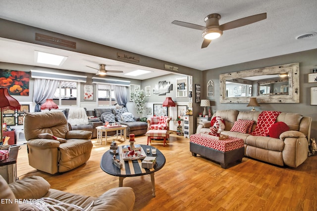 living room with a textured ceiling, wood-type flooring, and ceiling fan