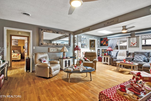 living room with ceiling fan, a textured ceiling, and hardwood / wood-style floors