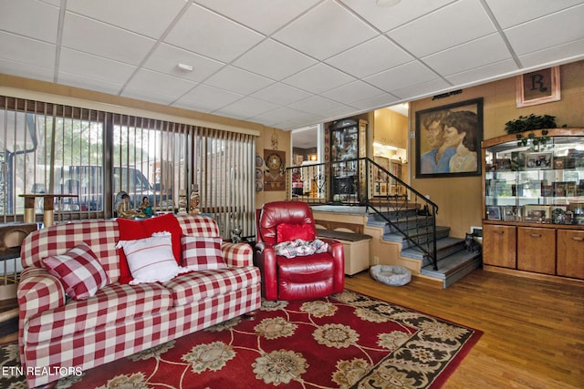 living room featuring wood-type flooring and a paneled ceiling