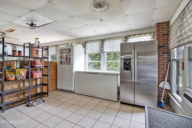 kitchen featuring a drop ceiling, white refrigerator, light tile patterned floors, and stainless steel fridge