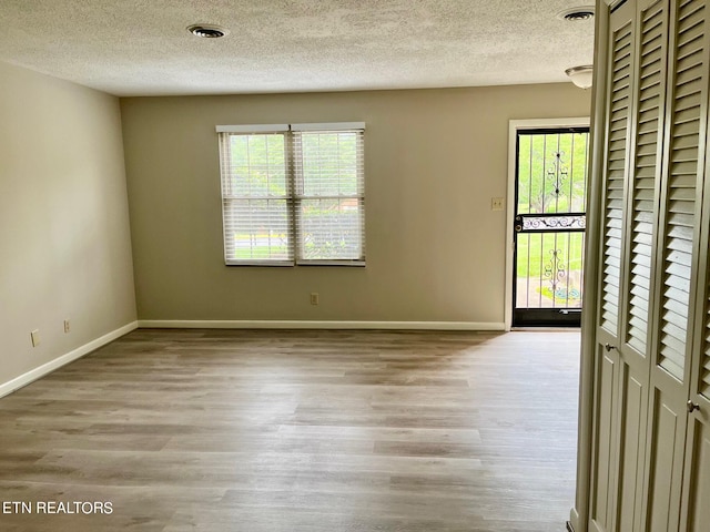 spare room with light hardwood / wood-style floors and a textured ceiling