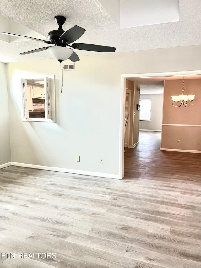 spare room featuring hardwood / wood-style flooring, a textured ceiling, and ceiling fan with notable chandelier