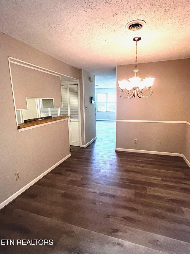 interior space featuring a notable chandelier, a textured ceiling, and dark hardwood / wood-style floors