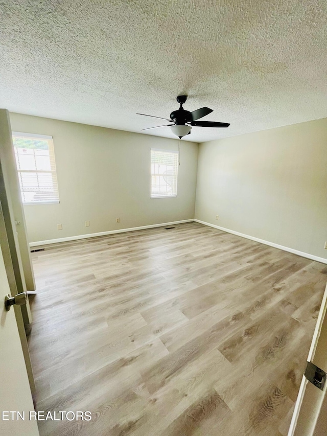 spare room featuring light hardwood / wood-style flooring, a textured ceiling, a healthy amount of sunlight, and ceiling fan