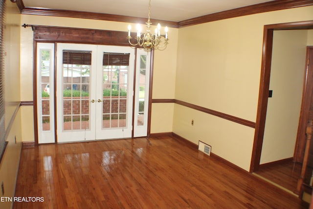 unfurnished dining area with an inviting chandelier, french doors, ornamental molding, visible vents, and wood finished floors