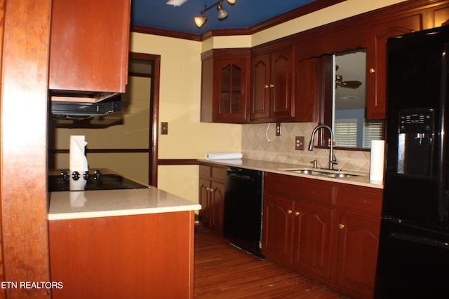 kitchen featuring light countertops, ornamental molding, decorative backsplash, a sink, and black appliances