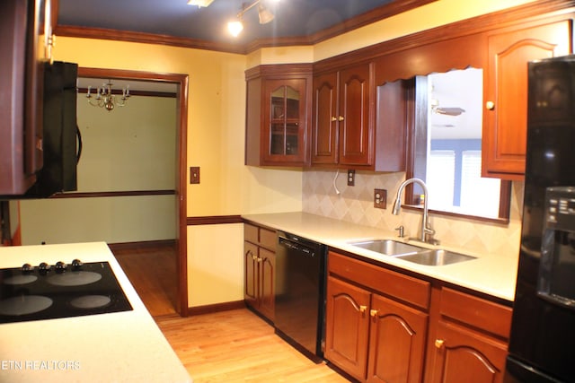 kitchen with light countertops, a sink, light wood finished floors, tasteful backsplash, and black appliances