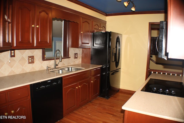 kitchen featuring light countertops, crown molding, dark wood finished floors, a sink, and black appliances