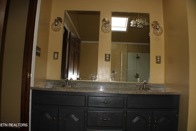 bathroom with an inviting chandelier, double vanity, a sink, and tiled shower