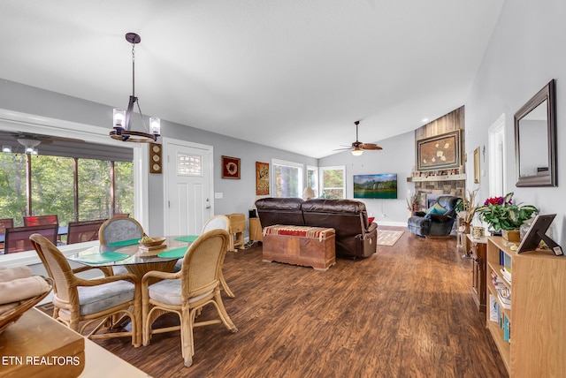 dining area featuring wood-type flooring, vaulted ceiling, ceiling fan, and a stone fireplace