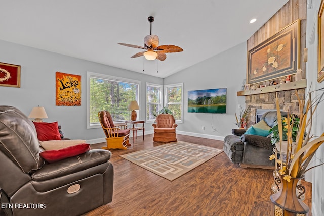 living room with ceiling fan, a stone fireplace, hardwood / wood-style flooring, and lofted ceiling