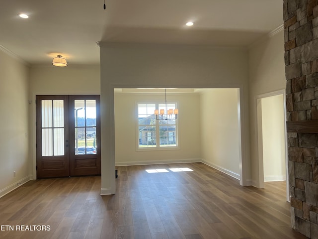 foyer entrance featuring an inviting chandelier, wood-type flooring, and ornamental molding