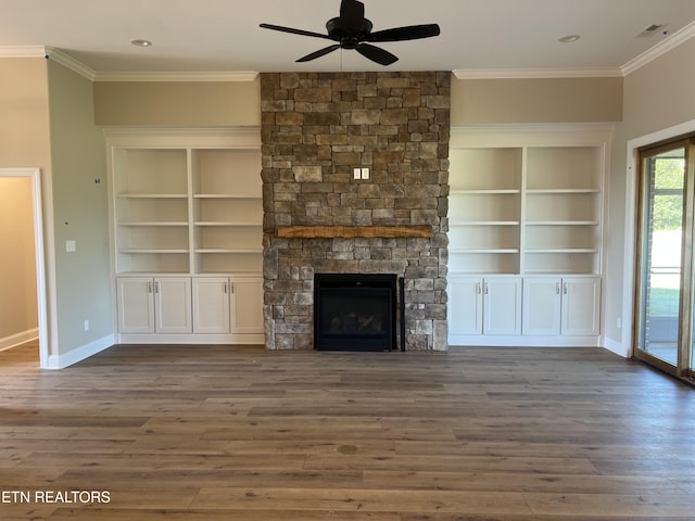 unfurnished living room featuring dark hardwood / wood-style floors, ceiling fan, a stone fireplace, and ornamental molding