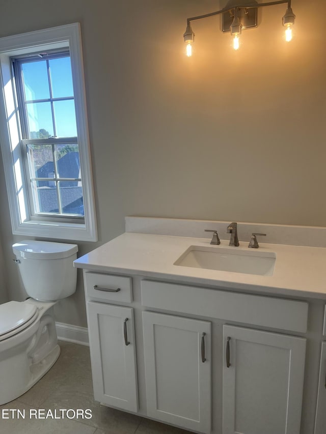 bathroom with toilet, vanity, and tile patterned floors