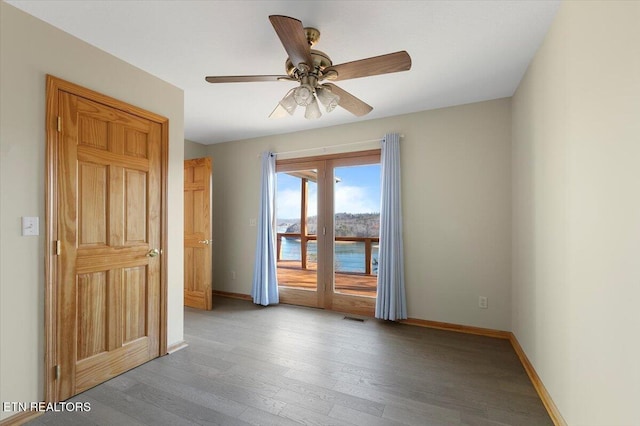 spare room featuring french doors, a water view, hardwood / wood-style flooring, and ceiling fan