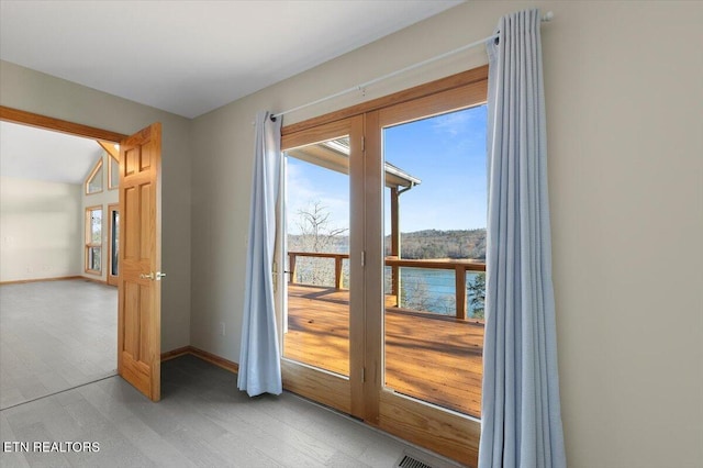 doorway to outside with hardwood / wood-style floors, a water view, and vaulted ceiling