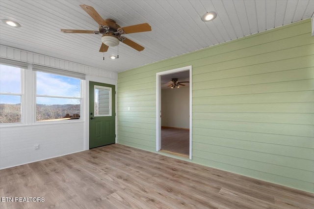 unfurnished sunroom with ceiling fan, a mountain view, and wooden ceiling