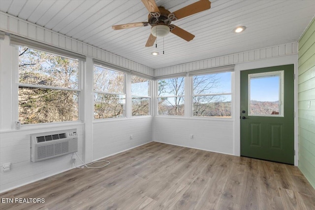 unfurnished sunroom with a wall mounted air conditioner, ceiling fan, a healthy amount of sunlight, and wood ceiling