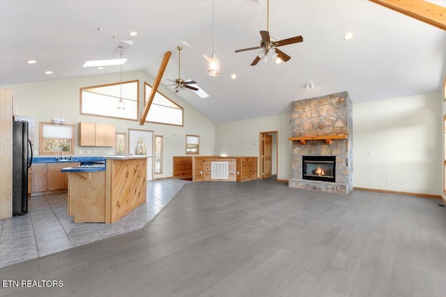 kitchen featuring light brown cabinetry, a skylight, black fridge, high vaulted ceiling, and light hardwood / wood-style floors