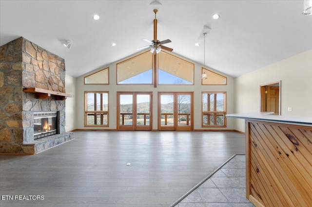 unfurnished living room featuring ceiling fan, a fireplace, high vaulted ceiling, and wood-type flooring