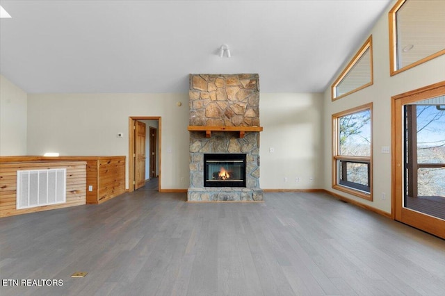 unfurnished living room featuring a stone fireplace, hardwood / wood-style floors, and vaulted ceiling