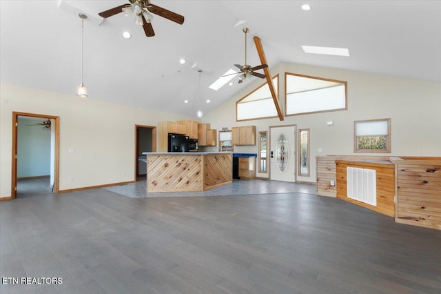 kitchen with dark wood-type flooring, high vaulted ceiling, black refrigerator, a skylight, and a wealth of natural light