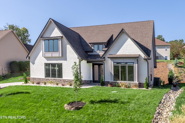 view of front of home featuring brick siding, central air condition unit, and a front yard