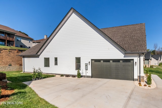 view of side of property with a lawn, concrete driveway, an attached garage, and a shingled roof