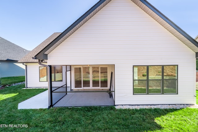 back of house featuring a yard, a shingled roof, and a patio