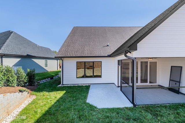 back of house with a patio area, a lawn, and roof with shingles