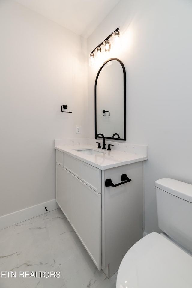 half bath featuring vanity, toilet, baseboards, and marble finish floor