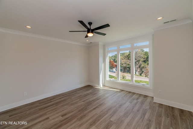 spare room featuring crown molding, wood finished floors, baseboards, and visible vents