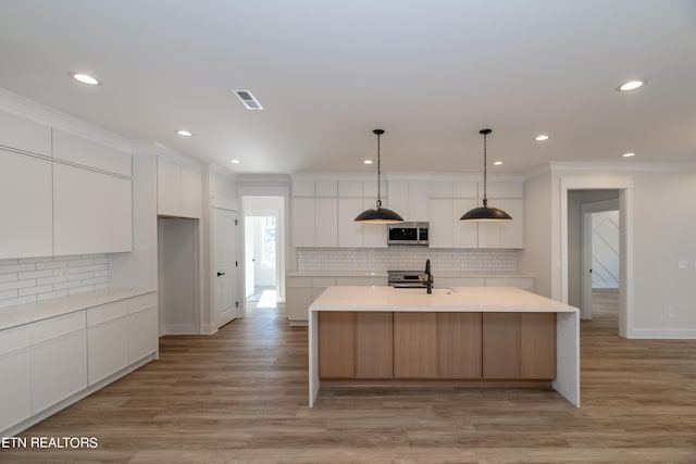 kitchen featuring visible vents, ornamental molding, stainless steel appliances, light countertops, and white cabinetry