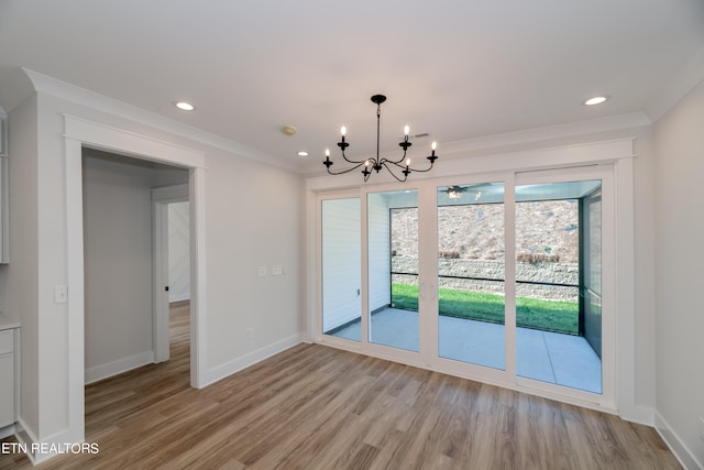 unfurnished dining area with light wood-type flooring, baseboards, a notable chandelier, and ornamental molding