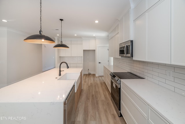 kitchen with a spacious island, decorative backsplash, light wood-style floors, appliances with stainless steel finishes, and white cabinetry