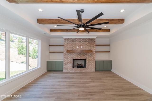 unfurnished living room featuring beam ceiling, baseboards, a brick fireplace, and light wood finished floors