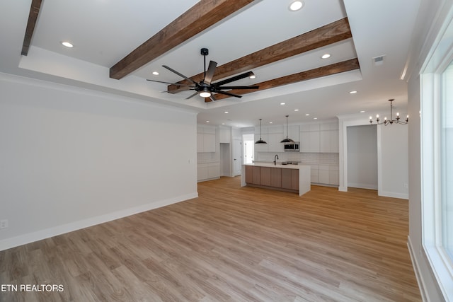 unfurnished living room featuring beam ceiling, ceiling fan with notable chandelier, baseboards, and light wood-style floors