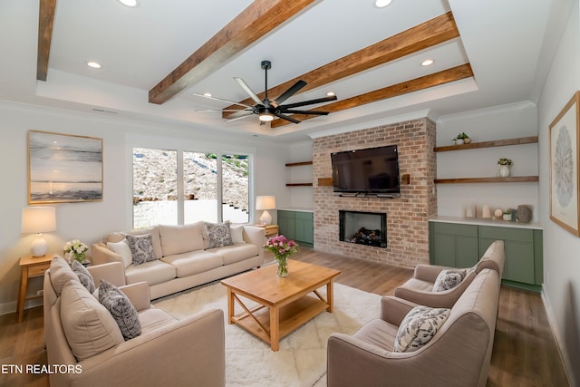 living room with a tray ceiling, beam ceiling, recessed lighting, a fireplace, and light wood-style floors