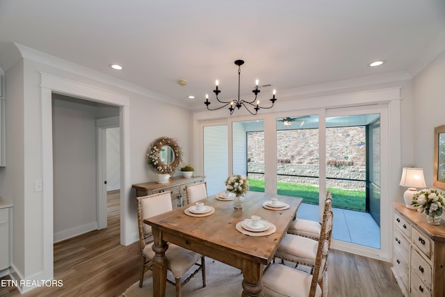 dining space featuring light wood-type flooring, an inviting chandelier, and ornamental molding