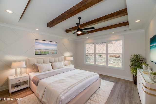 bedroom featuring beamed ceiling, wood finished floors, baseboards, and ornamental molding