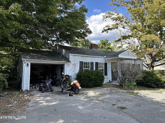view of front of house featuring driveway, a garage, and a chimney