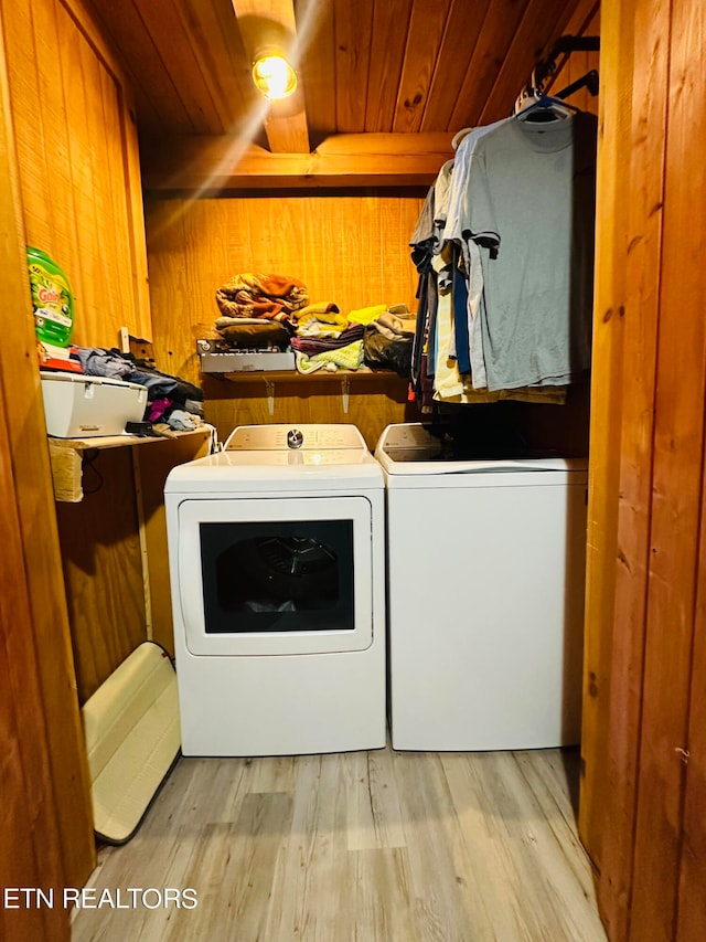 clothes washing area with ceiling fan, wood walls, light hardwood / wood-style flooring, washing machine and dryer, and wooden ceiling