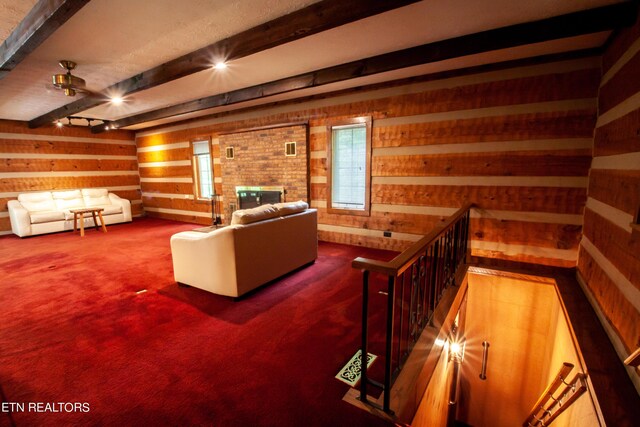 carpeted living room featuring beamed ceiling, a fireplace, and wood walls