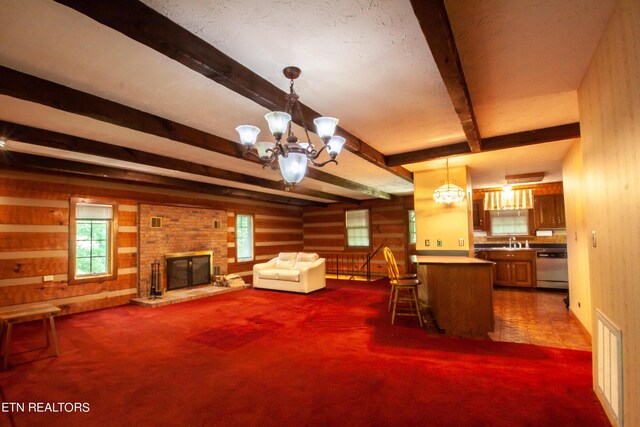 interior space with beam ceiling, dark colored carpet, a chandelier, and a brick fireplace