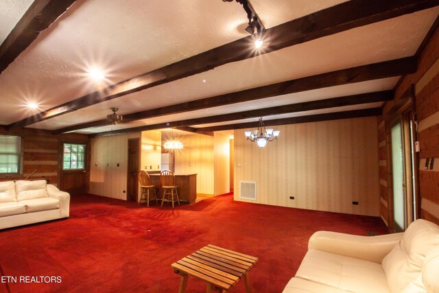 unfurnished living room with a notable chandelier, beam ceiling, wood walls, and carpet floors