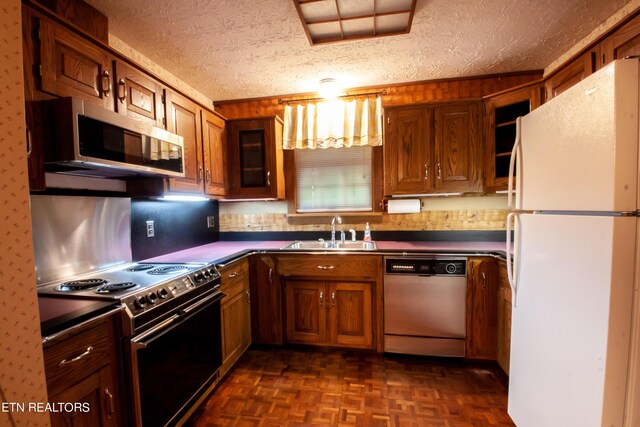 kitchen with sink, a textured ceiling, black / electric stove, dishwashing machine, and white fridge