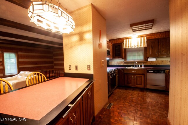 kitchen with a textured ceiling, kitchen peninsula, sink, and dishwashing machine