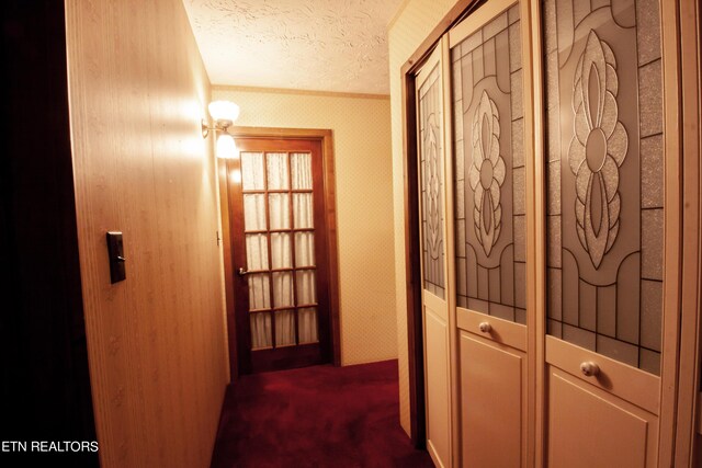 hall with a textured ceiling and carpet floors