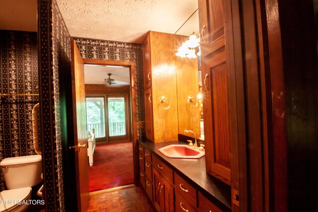 bathroom featuring vanity, a textured ceiling, parquet flooring, and toilet