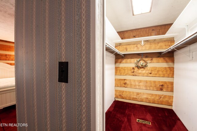 spacious closet with dark colored carpet